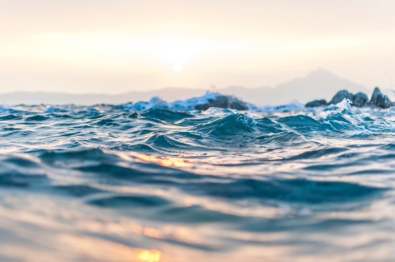 waves at sea with mountain in background at dusk