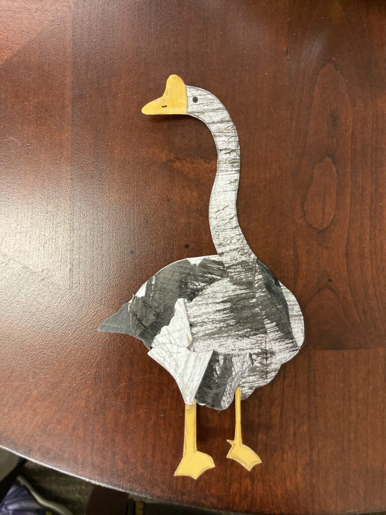 goose looking left, black and white out of paper cut out, yellow beak and feet. made in dean's office